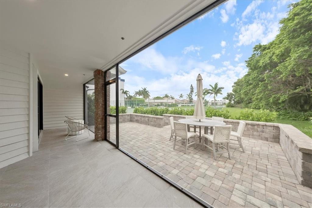 569 Park Shore Drive, Unit G5 Naples, FL 34103 - Photo 13 of 45 a view of a patio with a table chairs and a floor to ceiling window