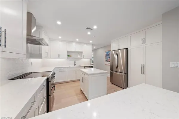 a kitchen with a refrigerator a sink and a stove top oven