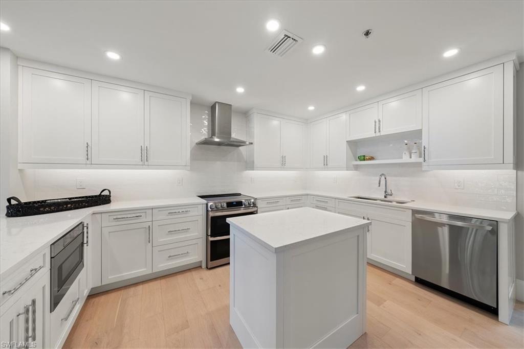 569 Park Shore Drive, Unit G5 Naples, FL 34103 - Photo 15 of 45 a kitchen with stainless steel appliances granite countertop a sink stove a refrigerator and white cabinets