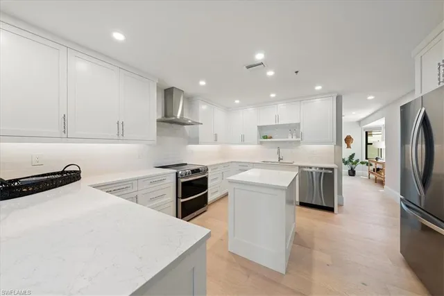 a kitchen with stainless steel appliances a stove a sink a refrigerator and white cabinets