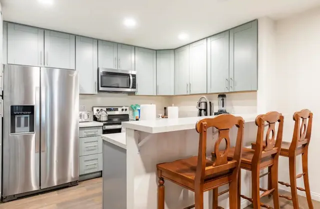 a kitchen with stainless steel appliances granite countertop a refrigerator a stove a sink and a microwave