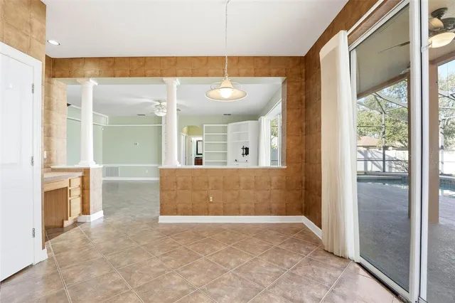 an empty room with wooden floor chandelier fan and windows