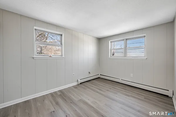 a view of empty room with wooden floor and window