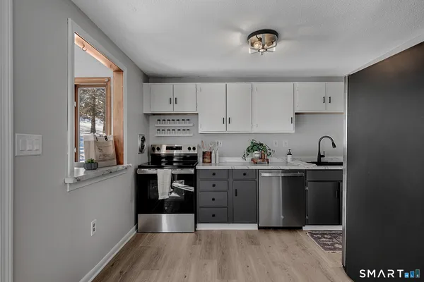 a kitchen with stainless steel appliances granite countertop a refrigerator a sink a stove and white cabinets