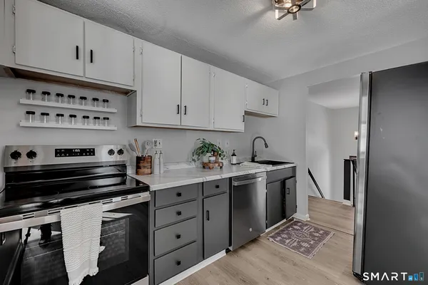 a kitchen with stainless steel appliances granite countertop a stove a sink a dining table and chairs with wooden floor