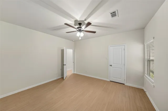 an empty room with chandelier fan and windows