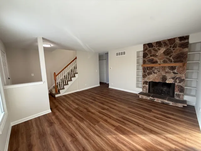 a view of a livingroom with wooden floor and a fireplace