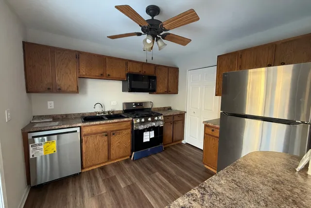 a kitchen with stainless steel appliances granite countertop a refrigerator a stove a sink and a microwave