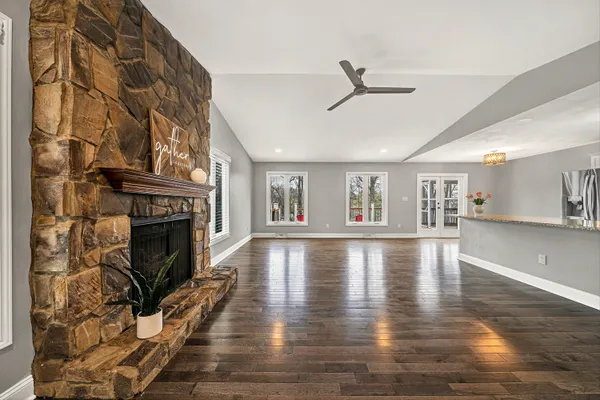 a view of an empty room with wooden floor and a fireplace