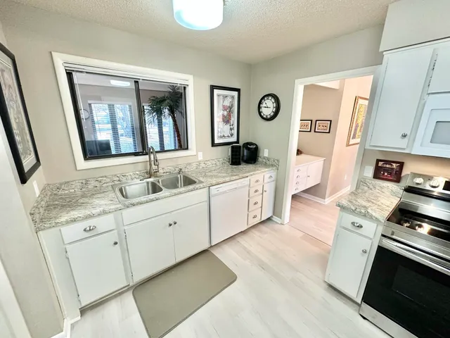 a large white kitchen with stainless steel appliances granite countertop a stove and a sink