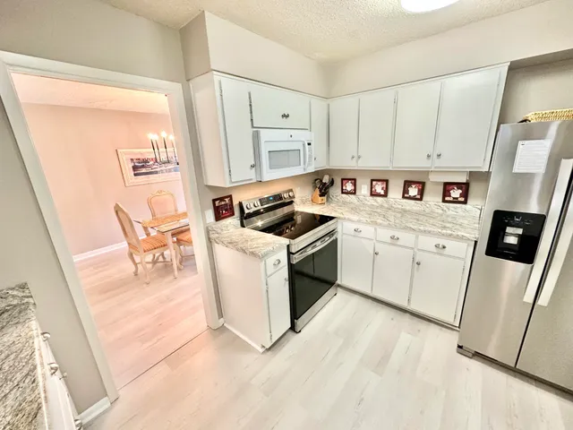 a kitchen with a white stove top oven and white countertops with cabinets