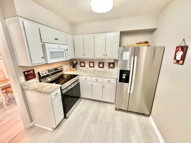 a kitchen with white cabinets and white appliances