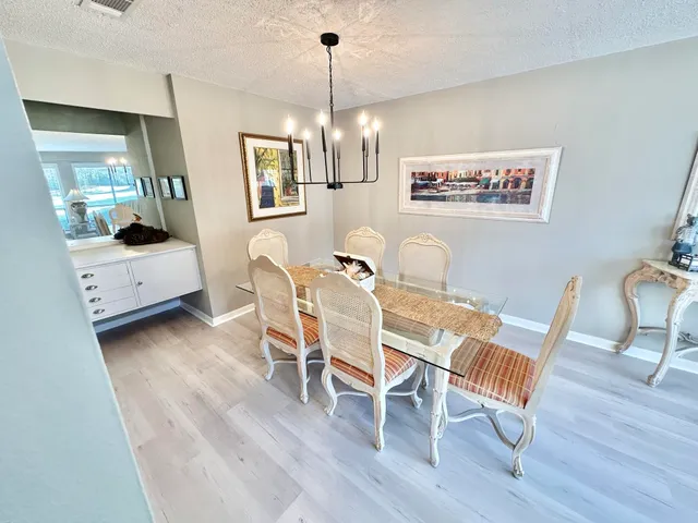 a dining room with wooden floor a chandelier a wooden table and chairs
