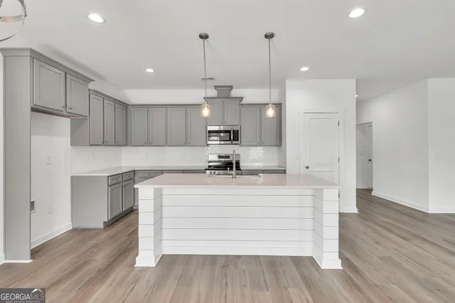 a kitchen with stainless steel appliances granite countertop a sink stove a refrigerator with white cabinets and wooden floor