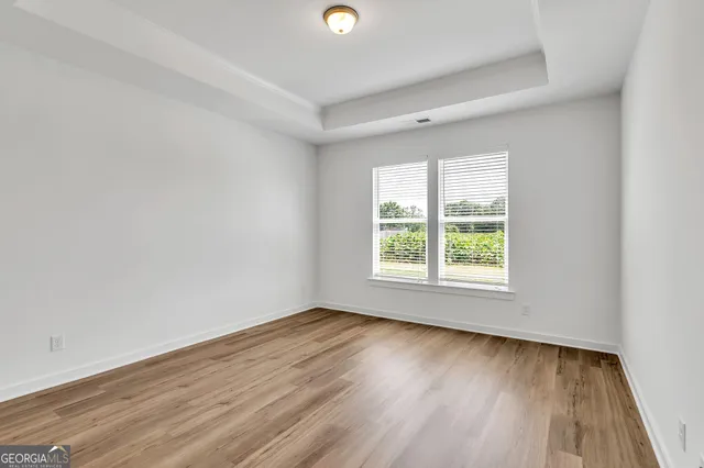 a view of an empty room with wooden floor and closet