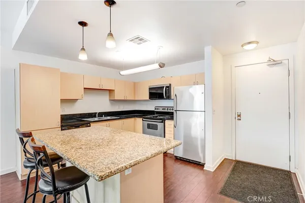 a kitchen with stainless steel appliances granite countertop a refrigerator a stove and a sink with wooden floor