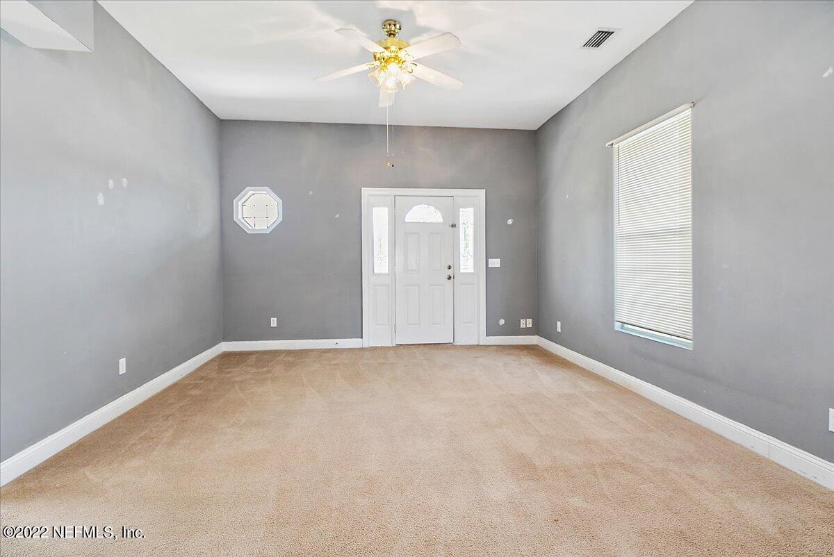 3404 St Augustine Road Jacksonville, FL 32207 - Photo 7 of 16 an empty room with a chandelier fan and windows