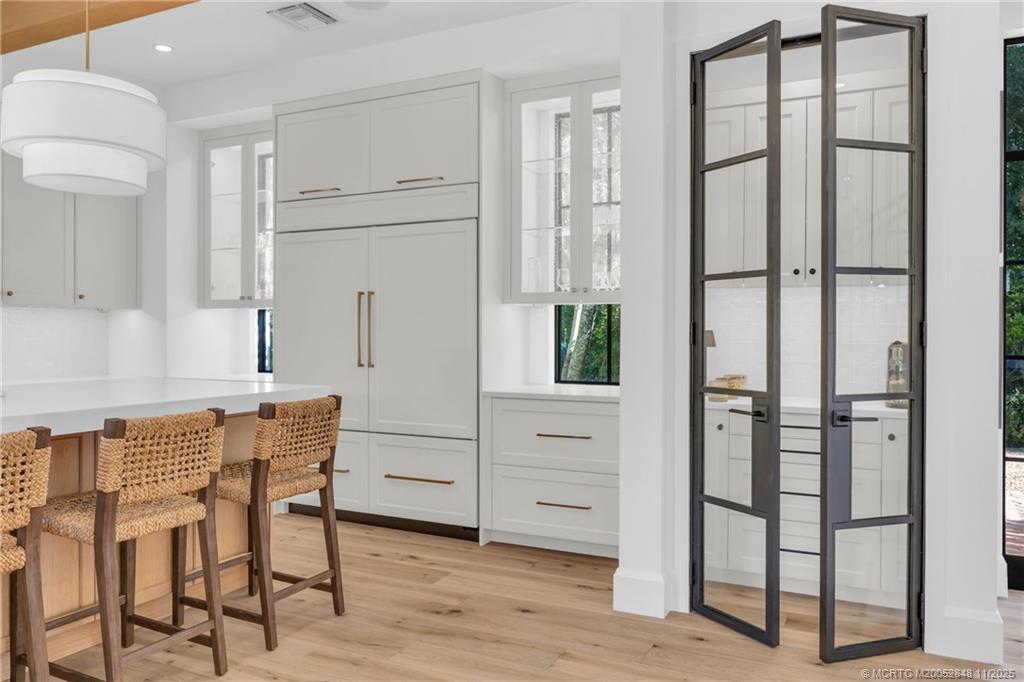 44 South Beach Road Hobe Sound, FL 33455 - Photo 19 of 73 a kitchen with white cabinets and wooden floor