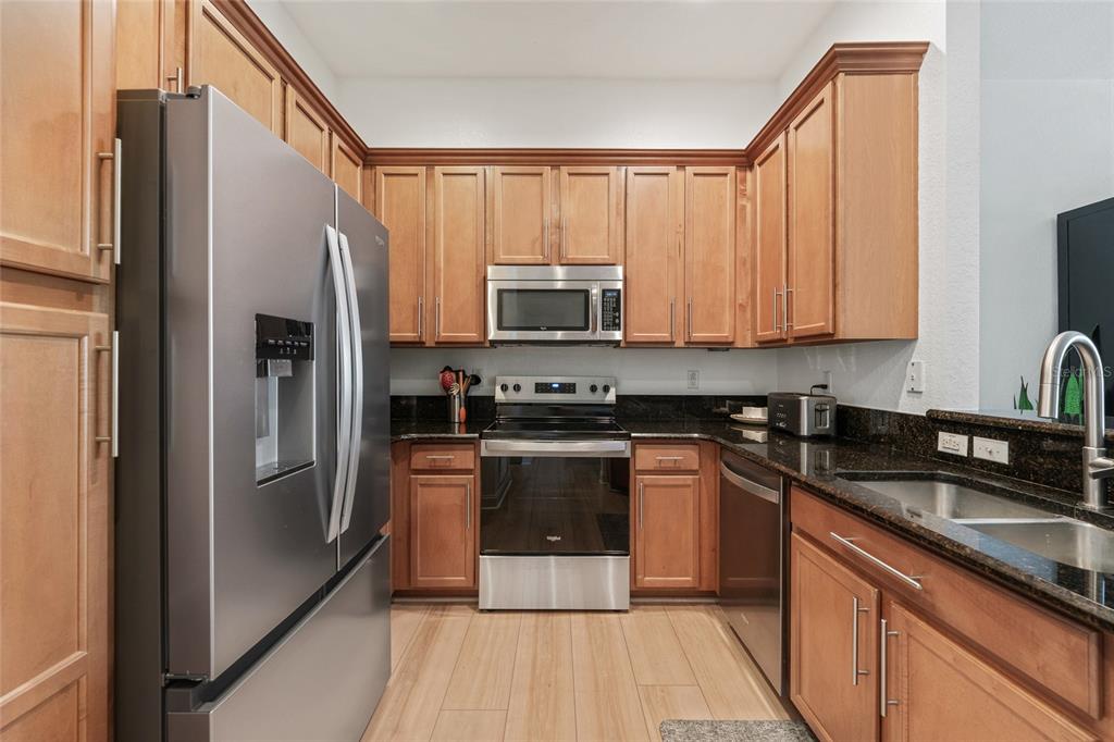 1819 Common Way Road, Unit 203 Orlando, FL 32814 - Photo 7 of 23 a kitchen with granite countertop a refrigerator stove and microwave