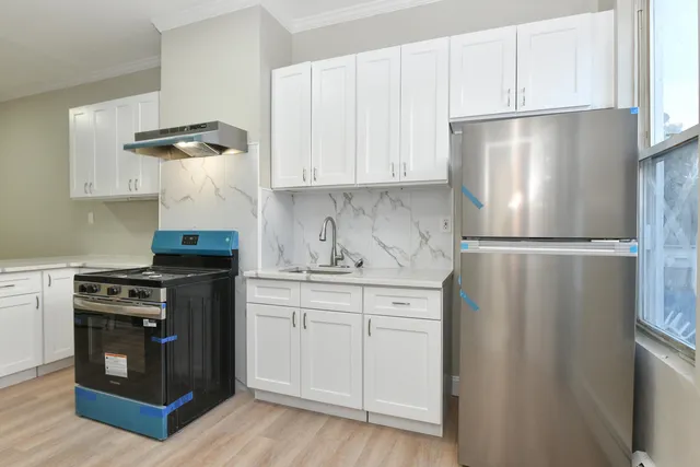 a kitchen with stainless steel appliances granite countertop a refrigerator a stove a sink and white cabinets