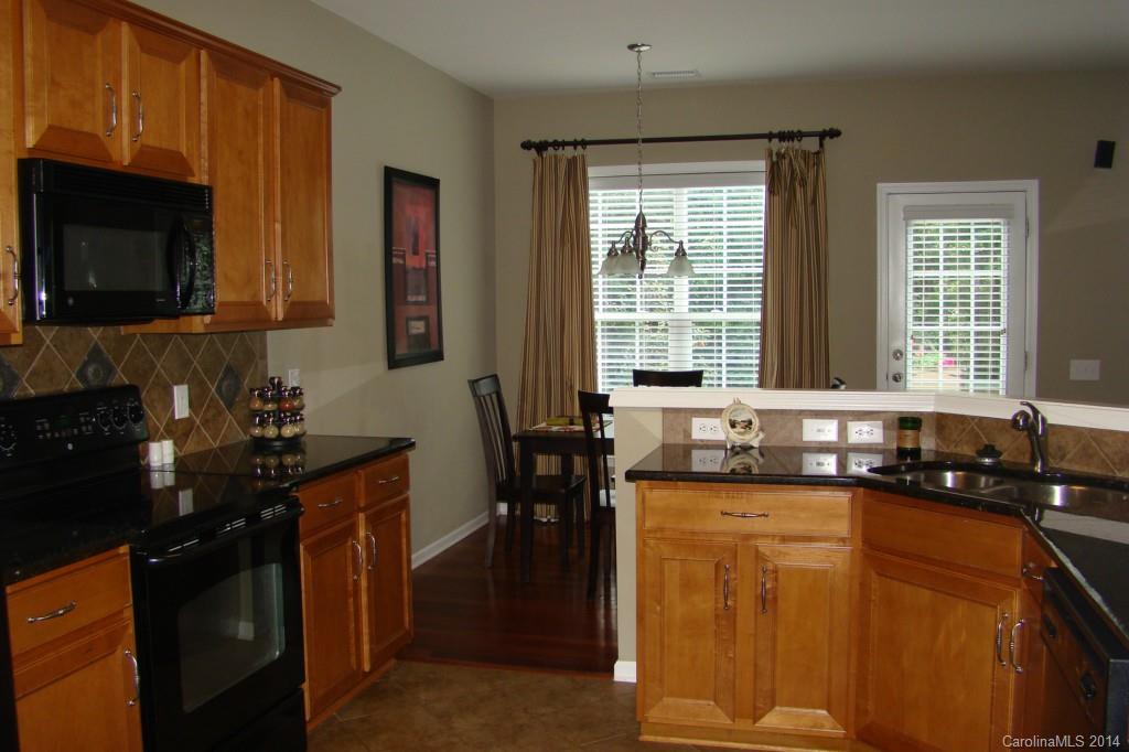 2204 Coltsgate Road Waxhaw, NC 28173 - Photo 5 of 15 a kitchen with granite countertop a sink a stove top oven and a dining table
