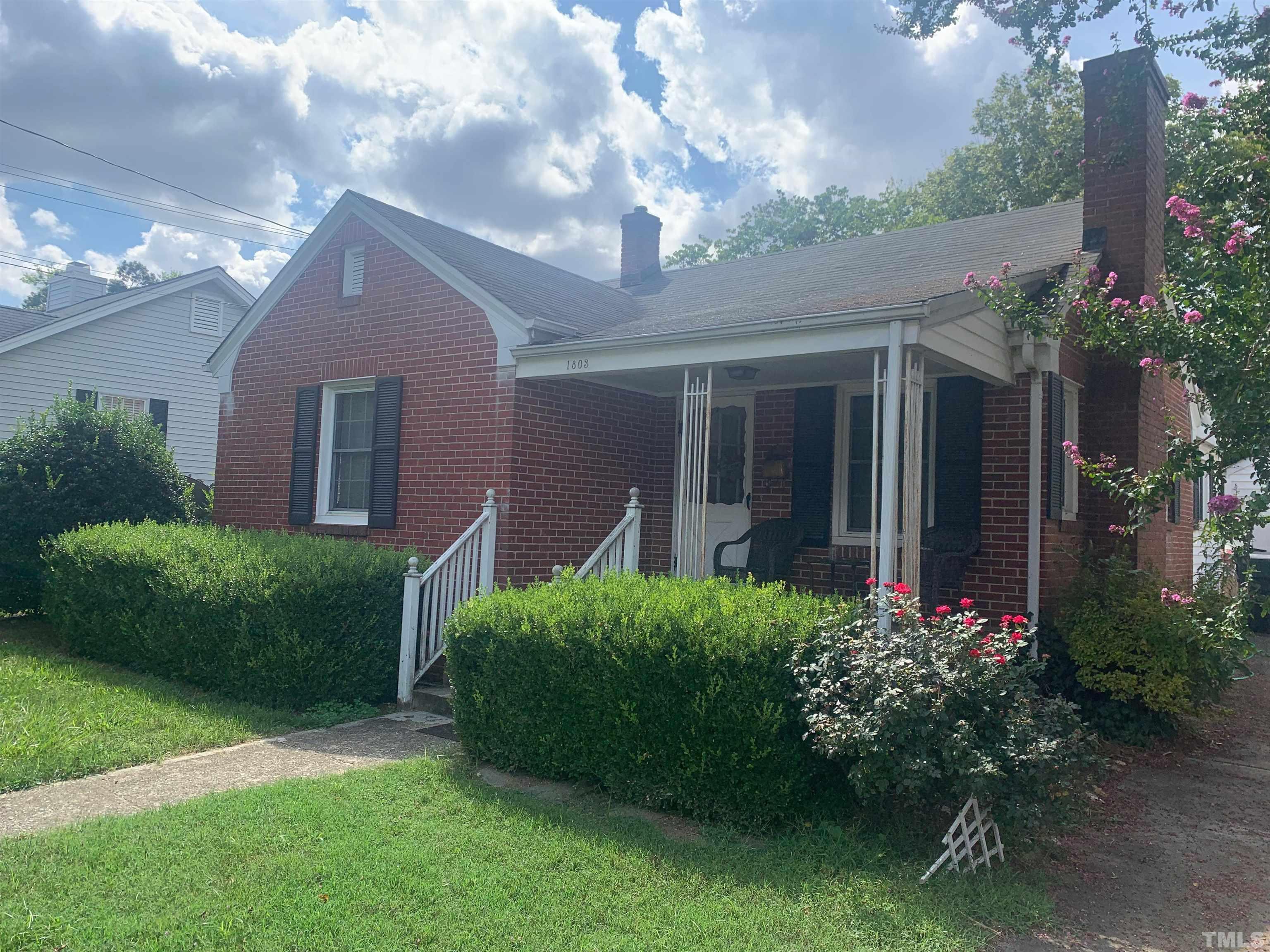 1803 Ridley Street Raleigh, NC 27608 - Photo 1 of 3 a view of a house with brick walls and a flower garden