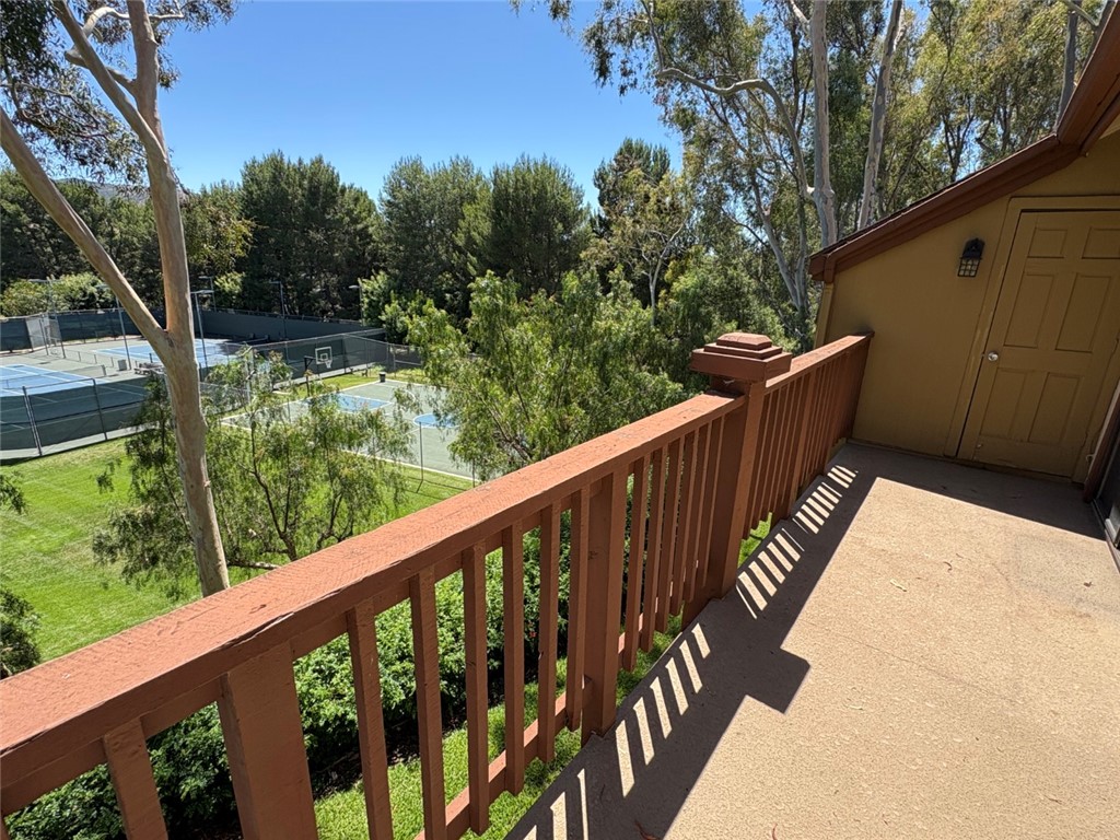 7 Rainbow, Unit 4 Irvine, CA 92603 - Photo 29 of 31 a balcony with wooden floor and trees in the back