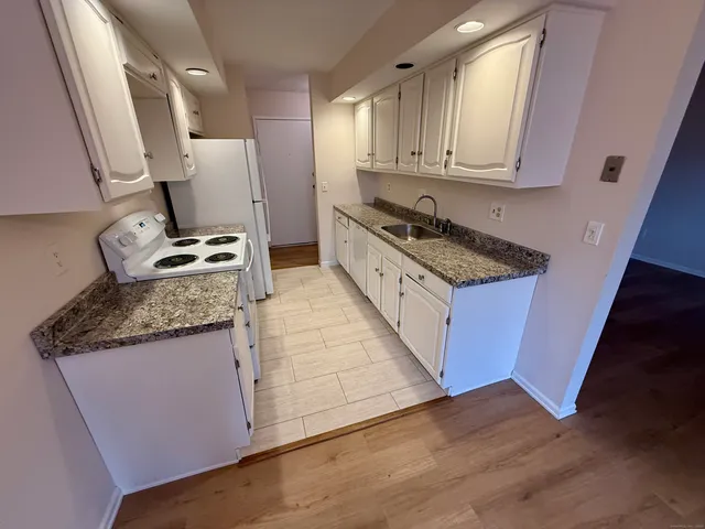 a kitchen with granite countertop a sink stove and cabinets
