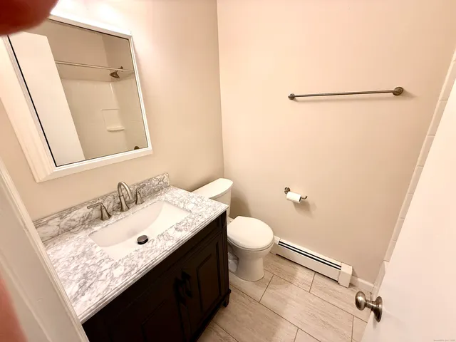 a bathroom with a granite countertop sink toilet and mirror