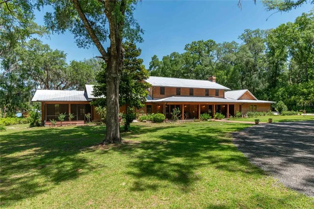a living room with stainless steel appliances furniture wooden floor and a kitchen view