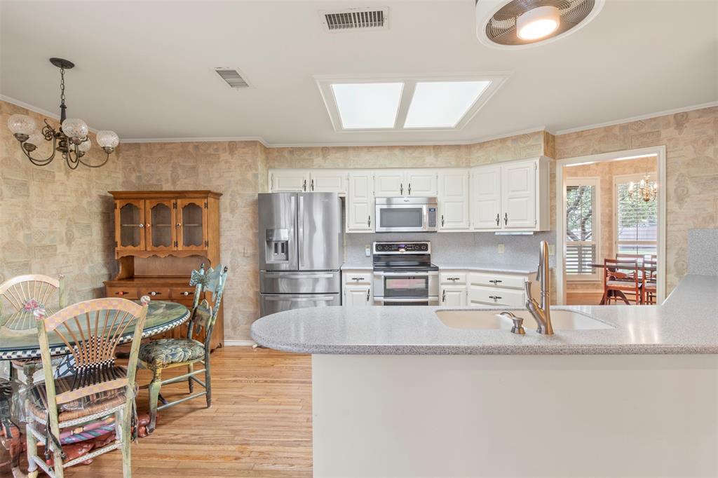 1104 Timberbend Trail Allen, TX 75002 - Photo 11 of 32 a kitchen with stainless steel appliances granite countertop a stove top oven a sink a dining table and chairs with wooden floor