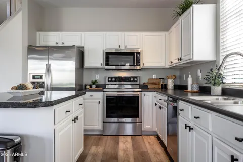 a kitchen with stainless steel appliances granite countertop a sink a stove and cabinets