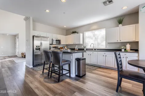 a kitchen with stainless steel appliances granite countertop a stove a sink a refrigerator white cabinets with wooden floor