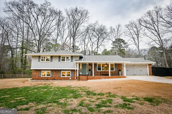 a front view of a residential houses with yard and trees in the background