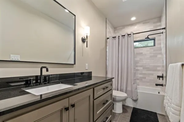 a bathroom with a sink a toilet a mirror and shower
