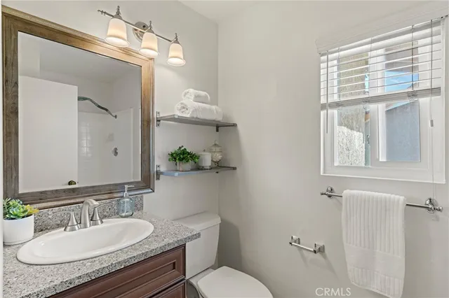 a bathroom with a granite countertop sink vanity mirror and toilet