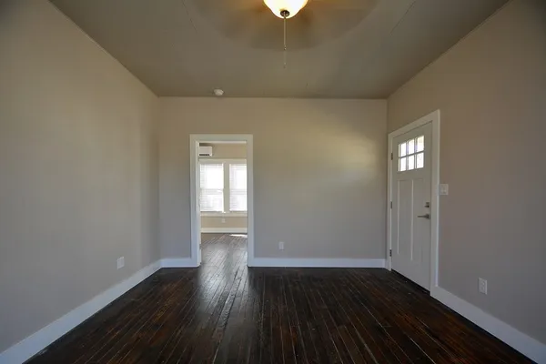 a view of an empty room with wooden floor and a window