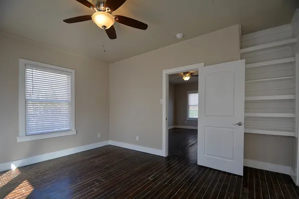 a view of an empty room with wooden floor and a window