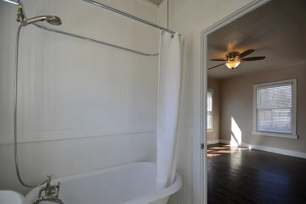 a view of empty room with wooden floor and fan