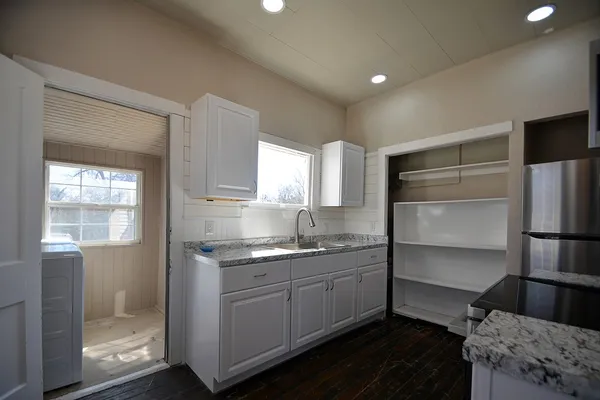 a kitchen with a sink appliances cabinets and a window