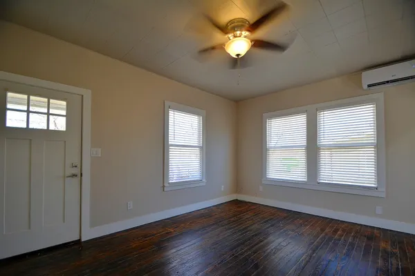 a view of an empty room with wooden floor and a window