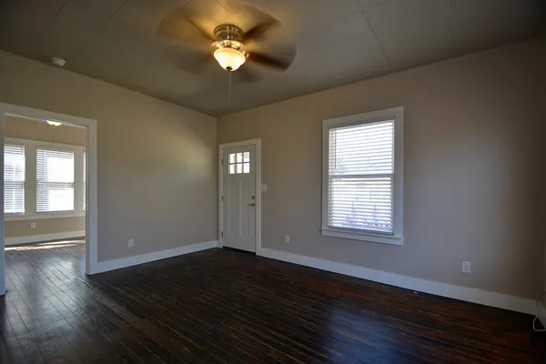 a view of empty room with wooden floor and fan