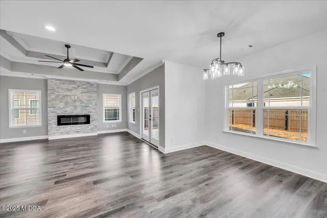 an empty room with wooden floor a fireplace a ceiling fan and windows