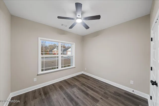an empty room with wooden floor chandelier fan and windows