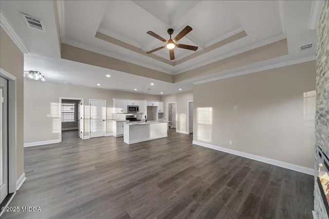 a view of an empty room with wooden floor and a ceiling fan