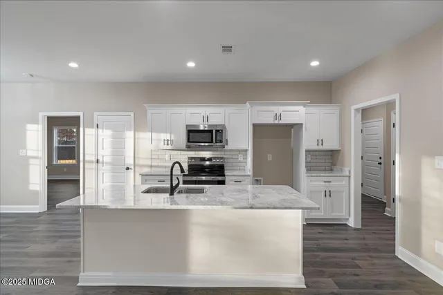 a large kitchen with stainless steel appliances kitchen island granite countertop a refrigerator and a stove top oven