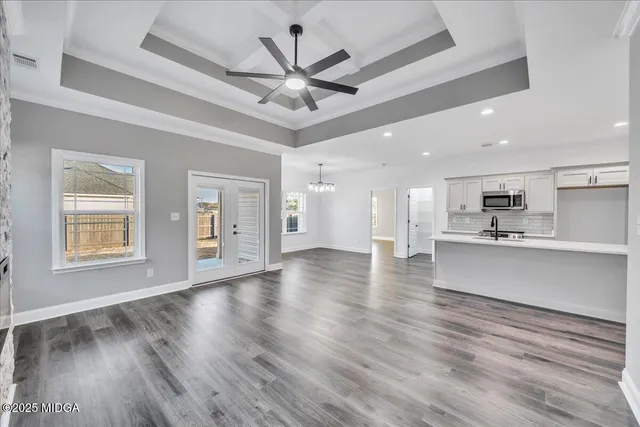 an empty room with wooden floor cabinet and windows
