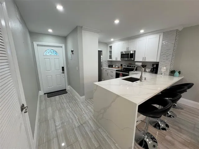 a kitchen with a sink a refrigerator and wooden floor
