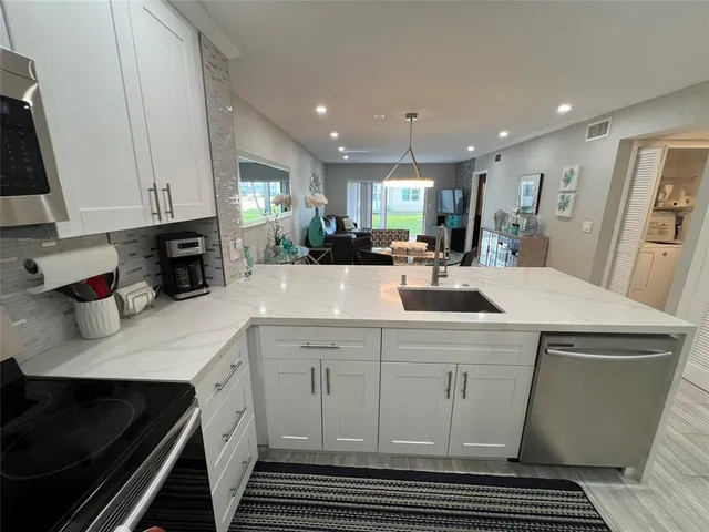 a kitchen with stainless steel appliances a sink a stove a refrigerator cabinets and a window