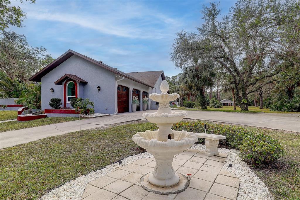 181 South Auburn Road Venice, FL 34292 - Photo 3 of 91 a view of a white house with a yard plants and large tree